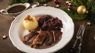 Weihnachtsgans mit Knödeln und Rotkohl auf einem Teller serviert
