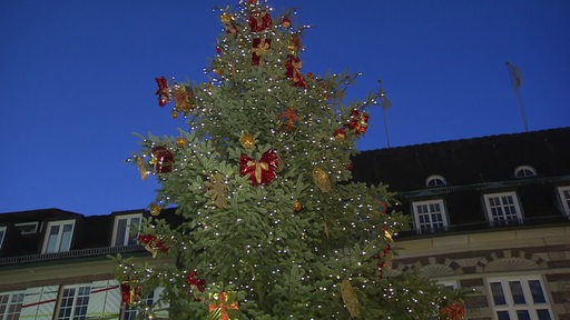 Ein Weihnachtsbaum mit vielen Lichtern und roten Dekogeschenke. 