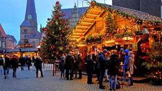 Beleuchteter Glühweinstand auf dem Bremer Weihnachtsmarkt, im Hintergrund die Liebfrauenkirche.