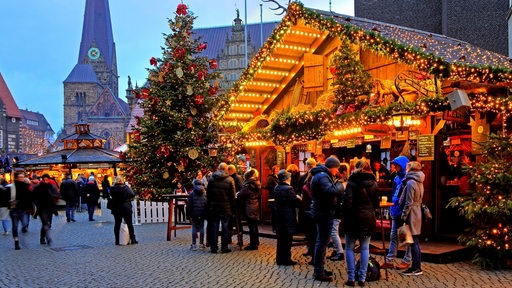 Beleuchteter Glühweinstand auf dem Bremer Weihnachtsmarkt, im Hintergrund die Liebfrauenkirche.