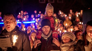 Eine Familie singt auf dem Bremen Vier Weihnachtssingen mit Kerzen in der Hand