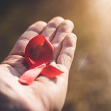 Auf einer Hand liegt eine rote Schleife