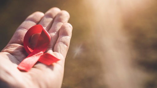 Auf einer Hand liegt eine rote Schleife