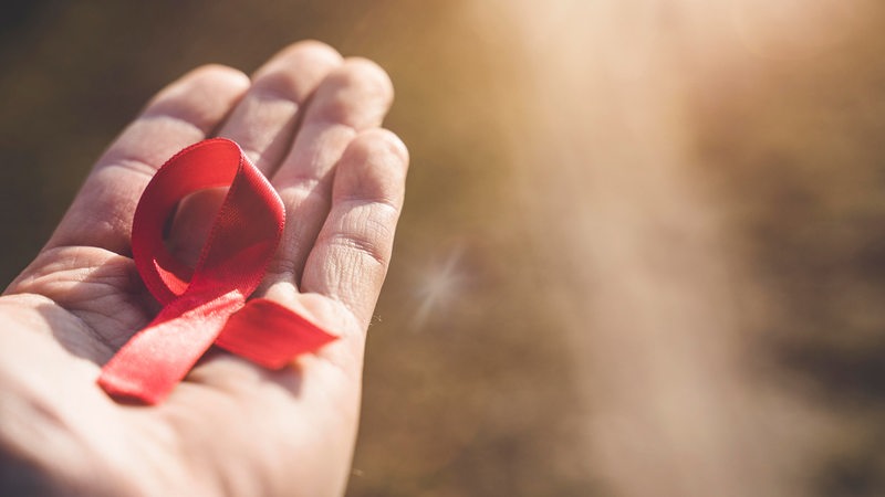 Auf einer Hand liegt eine rote Schleife