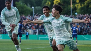 Drei junge Fußballspieler von Werder freuen sich über einen Sieg.