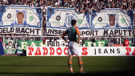 Werder-Fans äußern ihren Unmut über den Wechsel von Ailton und Krstajic zum FC Schalke 04 mit einem Banner mit der Aufschrift "Geld macht unseren Sport kaputt". 