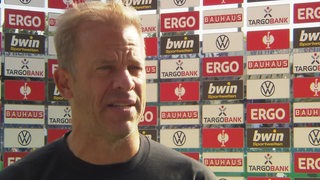 Werder-Trainer Markus Anfang nach dem Pokal-Spiel in Osnabrück beim Interview vor einer Werbewand.