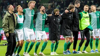 Die Werder-Spieler jubeln und Hüpfen vor den Fans