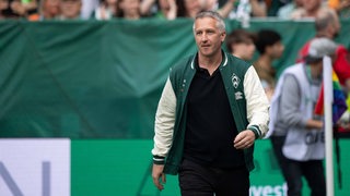 Frank Baumann trägt eine Werder-Jacke und läuft durch das Weser-Stadion.
