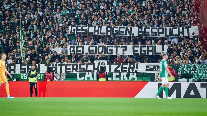 Beim Werder-Spiel gegen Hoffenheim halten Fans ein Banner mit der Aufschrift " "Geschlagen, bespuckt, beleidigt? Egal! Mia San Täterschützer!" hoch.