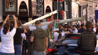 Ein Werder-Fan hat den Teil eines Tores mitgenommen und geht damit über den Sielwall