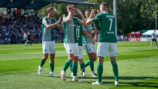 Die Werder-Spieler klatschen sich nach dem Führungstreffer gegen Viktoria Köln ab.