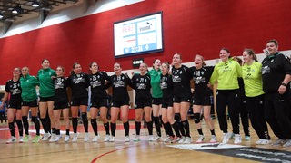 Die Werder-Handballerinnen feiern Arm in Arm hüpfend einen Sieg.
