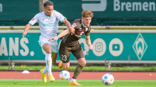 Werder-Spieler Felix Agu liefert sich ein Laufduell mit seinem Pauli-Gegenspieler.