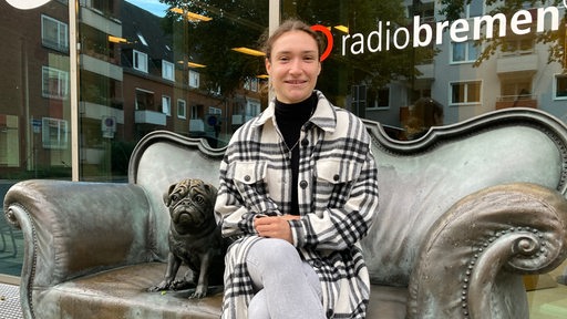 Werder-Spielerin Sophie Weidauer sitzt auf dem Bronzesofa bei Radio Bremen und lächelt.