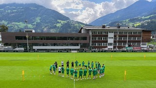 Die Werder-Spieler versammeln sich auf einem Trainingsplatz im Zillertal im Kreis.