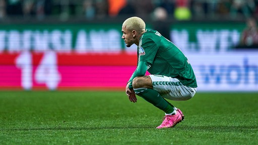 Justin Njinmah sitzt frustriert nach dem Spiel gegen den BVB in einer Kniehocke auf dem Rasen.