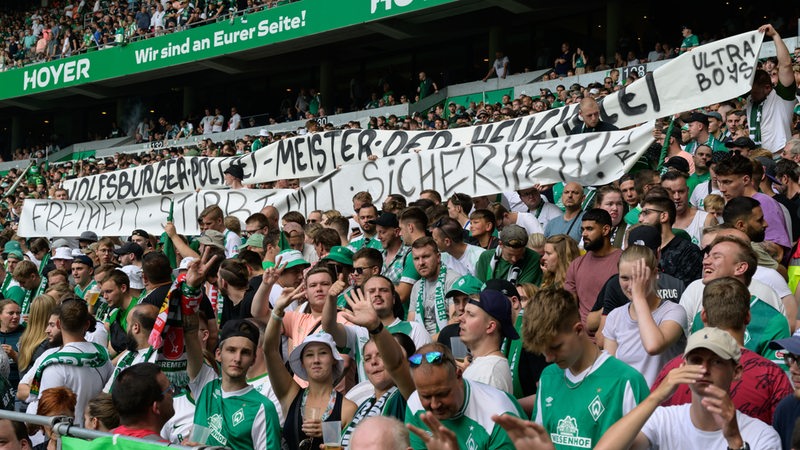 Werder-Fans halten Banner hoch mit den Aufschriften "Wolfsburger Polizei Meister Heuchelei" sowie "Freiheit stirbt mit Sicherheit"