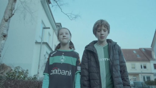 Zwei Kinder gehen durch Bremen und tragen Werder-Trickots.