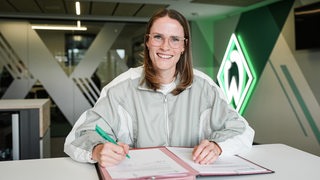 Reena Wichmann unterschreibt ihren Vertrag in der Geschäftsstelle des SV Werder Bremen