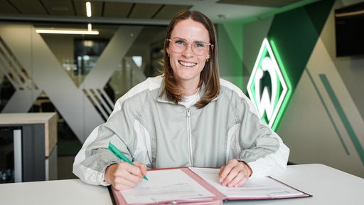 Reena Wichmann unterschreibt ihren Vertrag in der Geschäftsstelle des SV Werder Bremen