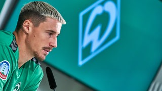 Marco Friedl sitzt auf dem Podium.