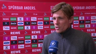 Werders Sportlicher Leiter Clemens Fritz nach der Niederlage in Köln beim Interview vor einer Werbewand.