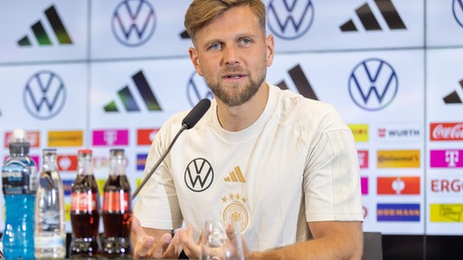 Niclas Füllkrug sitzt auf dem Podium. 