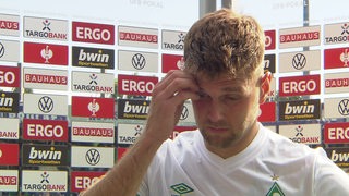 Werder-Stürmer Niclas Füllkrug fasst sich nachdenklich an die Stirn beim Interview nach dem Pokal-Aus in Osnabrück.