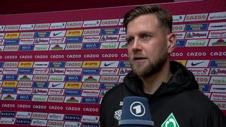 Werder-Stürmer Niclas Füllkrug nach dem Spiel beim Interview vor einer Werbewand.
