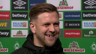 Werder-Stürmer Niclas Füllkrug grinst breit während eines Interviews nach dem Spiel gegen Schalke.