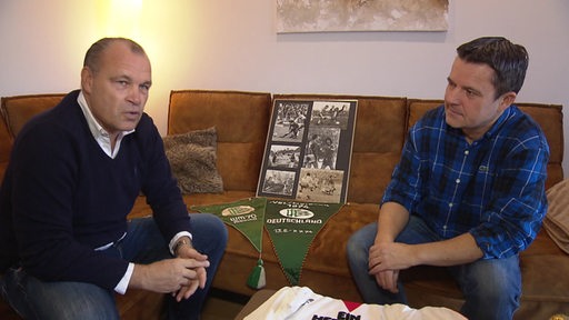 Andree Höttges und Trödel-Experte Marco Heuberg sehen Memorabilia aus der Fußball-Karriere von Werder-Legende Horst-Dieter Höttges durch.