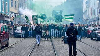 Werder-Fans marschieren mit Fahnen zum Weser-Stadion