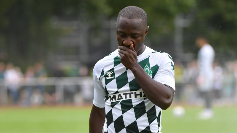 Naby Keita hält sich die Hand vor das Gesicht.