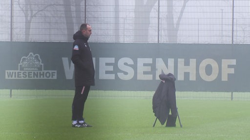 Der Werder-Trainer Ole Werner auf einem nebligen Spielfeld.