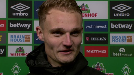 Werder-Profi Amos Pieper vor einer Werbewand bei einem Interview nach dem Spiel gegen Wolfsburg.