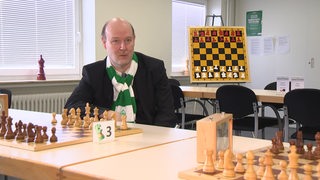 Oliver Höpfner sitzt vor einem Schachbrett.