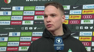 Werder-Spieler Niklas Schmidt steht vor einer Werbewand beim Interview nach dem Spiel.