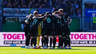 Spieler von Werder Bremen schwören sich in einem Kreis auf ein Spiel ein.