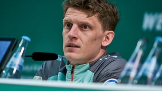 Jens Stage sitzt auf dem Podium und beantwortet Fragen.