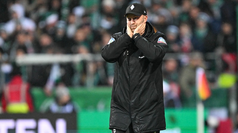 Werders Cheftrainer Ole Werner steht am Spielfeldrand und hält sich die Hände vor das Gesicht.