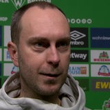 Werder-Trainer Ole Werner steht vor einer Werbewand beim Interview nach dem Spiel gegen Wolfsburg.