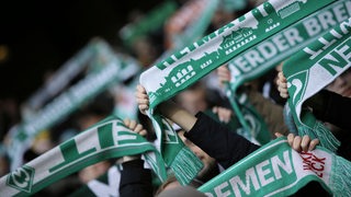 Werder-Fans halten ihre Schals in die Luft (Archivbild)