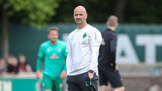 Werders U23-Trainer Christian Brand steht nachdenklich mit den Händen in den Hosentaschen am Spielfeldrand.
