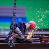 Ein Arbeiter schleift ein Metallstück.