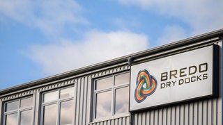 An einer Gebäudewand hängt ein Schild mit der Aufschrift "Bredo Dry Docks".