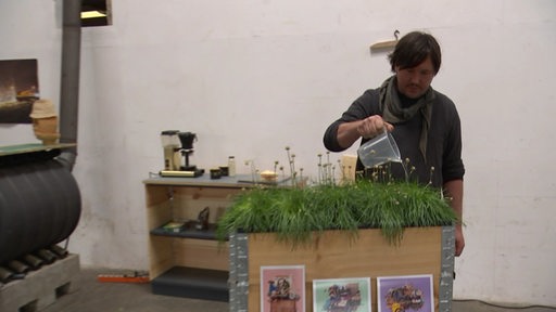Klaas Seekamp gießt Blumen in seinert Werkstatt