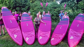 Die Frauen der Weser Pinkies mit pinken Stand Up Paddle Boards.