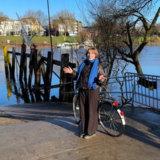 Reporterin steht mit einem Fahrrad vor der Weser.
