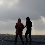 Trotz starkem Wind und Sturmböen gehen auf der Seebäderkaje in Bremerhaven ein Mann und eine Frau spazieren.